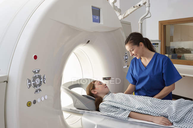 Female radiographer reassuring girl going into CT scanner — Stock Photo