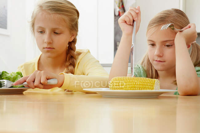 Meninas cutucando legumes no prato — Fotografia de Stock