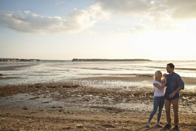 Jeune couple profitant de la plage au coucher du soleil — Photo de stock