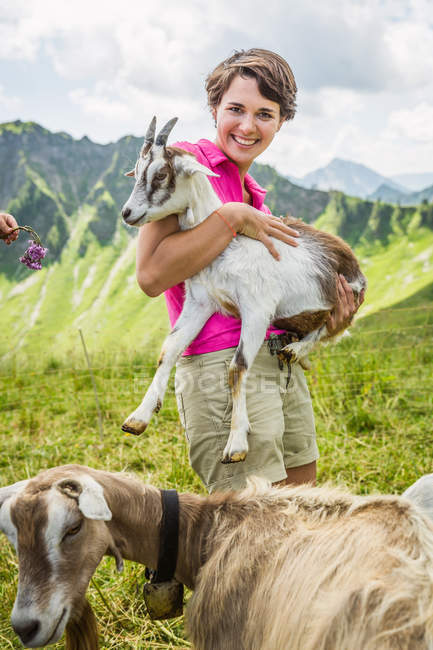 Mujer joven sosteniendo cabrito cabra, Tirol, Austria - foto de stock