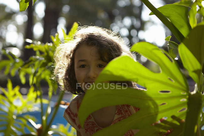 Young girl  smiling, standing amongst foliage — Stock Photo