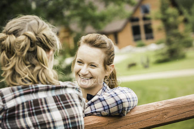 Frau lehnt lächelnd an Zaun — Stockfoto