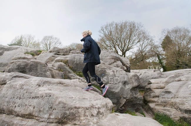 Metà corridore femminile adulto che corre su formazione rocciosa — Foto stock