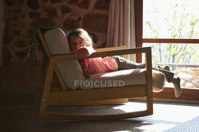 Portrait of young girl lying on rocking chair — Stock Photo