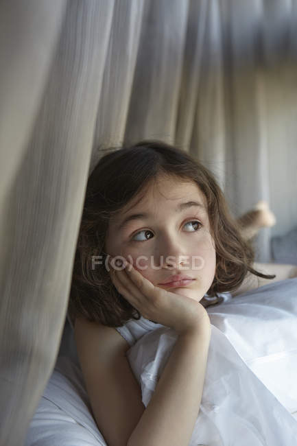 Дівчина сидить на ліжку дивиться вбік — стокове фото
