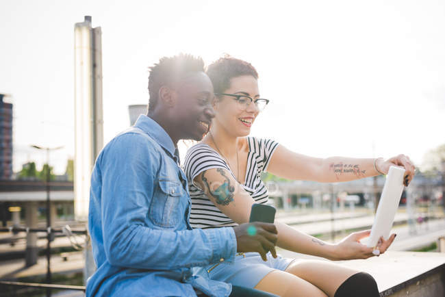 Пара, дивлячись на цифровий планшет, посміхаючись, Мілан, Італія — стокове фото