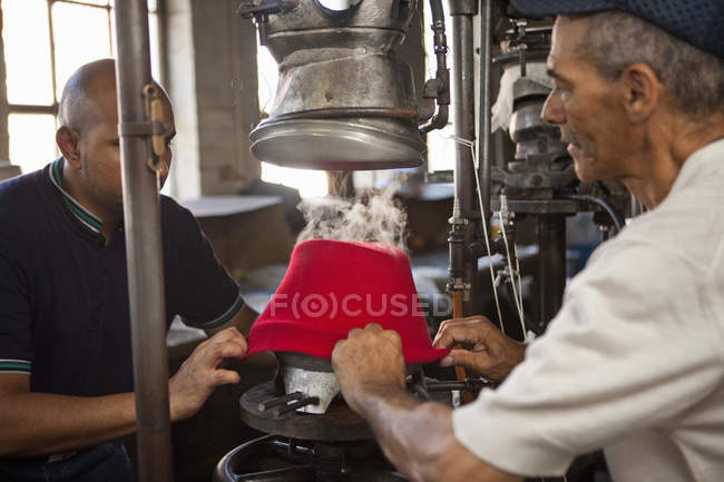 Шляпники растягивая ткань на плесени в мастерской — стоковое фото