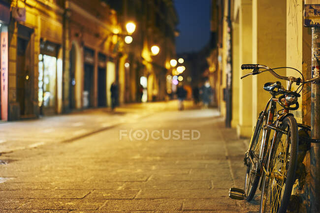 Bicicleta encostada à parede de rua à noite, Bolonha, Itália — Fotografia de Stock