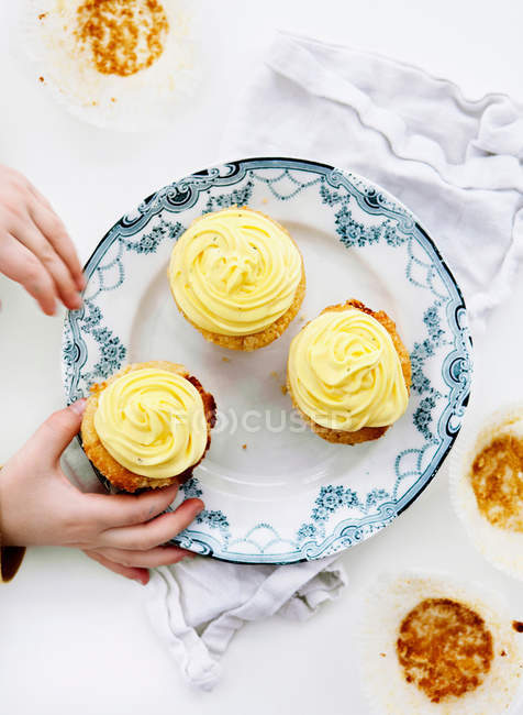 Imagem cortada de criança pegando cupcakes da placa — Fotografia de Stock