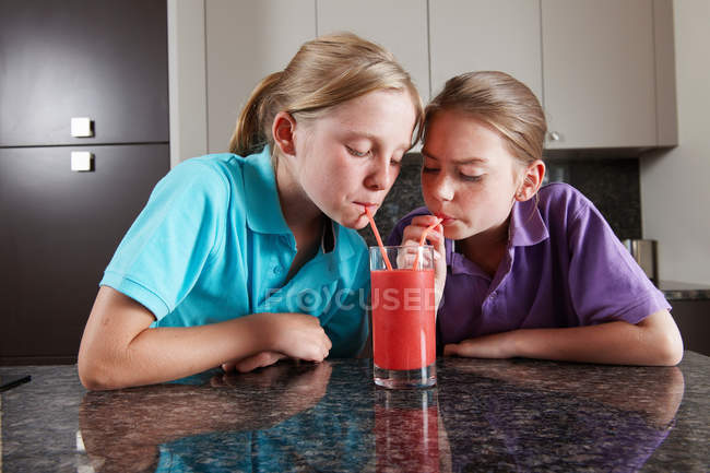 Meninas bebendo suco de frutas com palhas — Fotografia de Stock