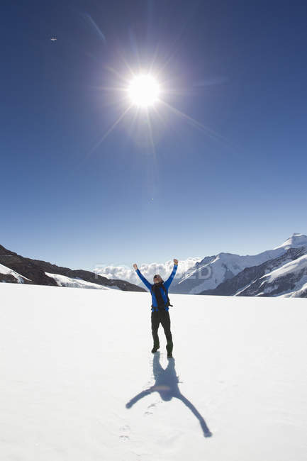 Мужской турист празднует в заснеженном ландшафте, Jungfrauchjoch, Гриндельвальд, Швейцария — стоковое фото