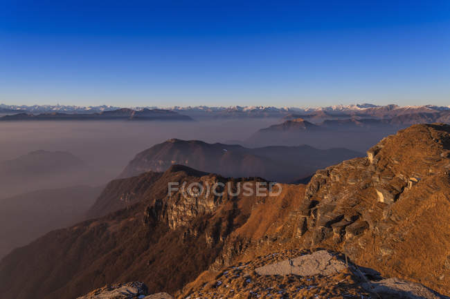 Paysage brumeux élevé avec des montagnes recouvertes de neige lointaine — Photo de stock