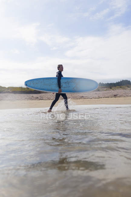 Surfista che trasporta tavole da surf in mare, Baia delle Isole, Nuova Zelanda — Foto stock