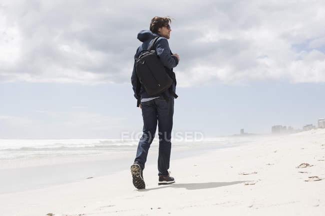 Vue arrière du jeune homme se promenant seul sur la plage, Western Cape, Afrique du Sud — Photo de stock