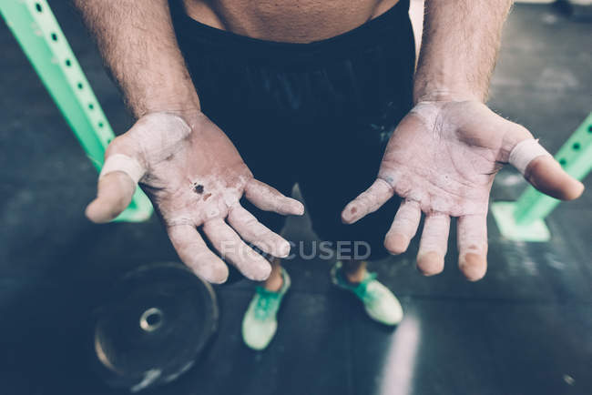 Gros plan des mains crayées de l'entraîneur croisé masculin dans la salle de gym — Photo de stock