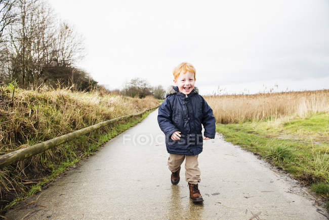 Enfant mâle courant le long de la route rurale — Photo de stock