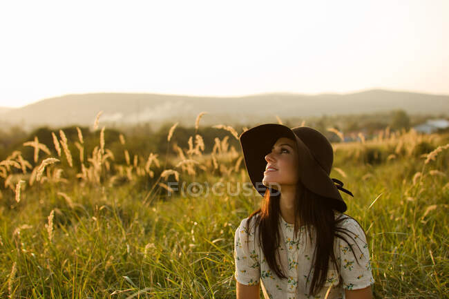 Женщина в шляпе сидит в траве — стоковое фото