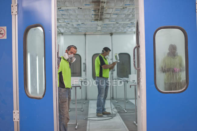 Hommes travaillant dans l'atelier de peinture par pulvérisation — Photo de stock