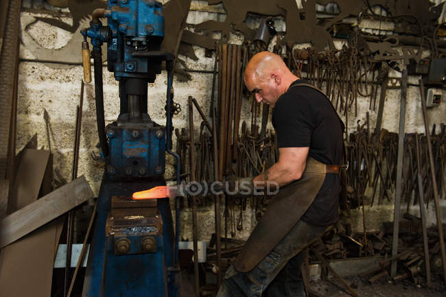 Hombre herrero caucásico trabajando en taller - foto de stock