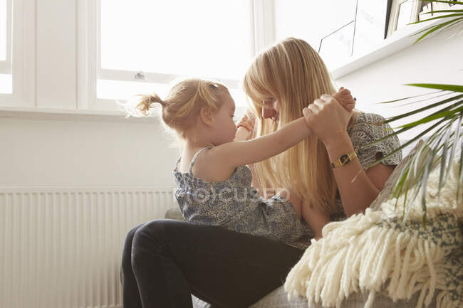 Середня доросла жінка і дочка малюка грають на дивані — стокове фото