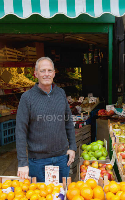 Greengrocer in front of his stall — Stock Photo