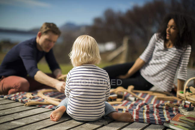 Boy sitting on wooden decking, rear view — Stock Photo