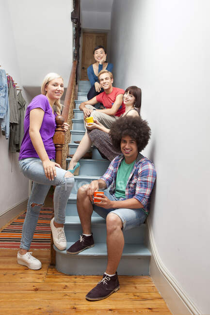 Retrato de compañeros de piso sentados en escaleras - foto de stock