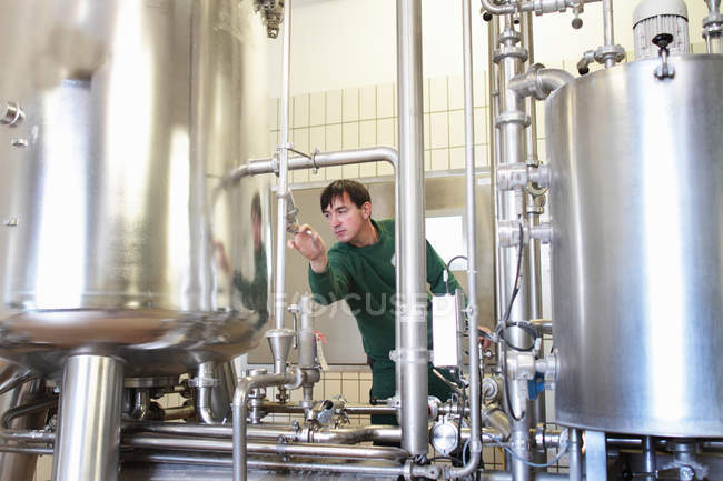 Cervejaria trabalhador operando máquina na fábrica — Fotografia de Stock