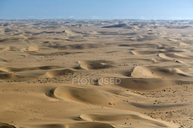 Воздушный вид песчаных дюн под голубым небом — стоковое фото