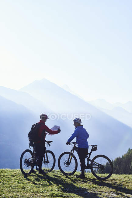 Ciclistas de montaña con mapa, Valais, Suiza - foto de stock