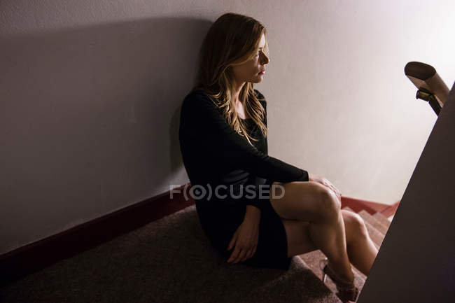 Mature woman sitting on staircase, looking away — Stock Photo