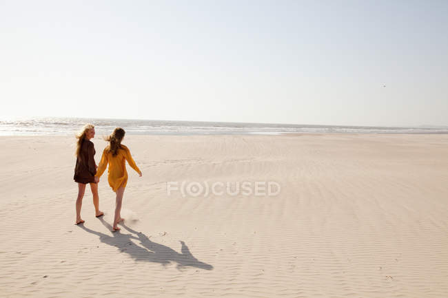 Mãe e filha andando na praia de areia — Fotografia de Stock