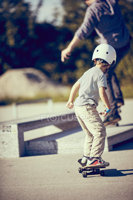 Маленький хлопчик в шоломі скейтбординг в парку — стокове фото