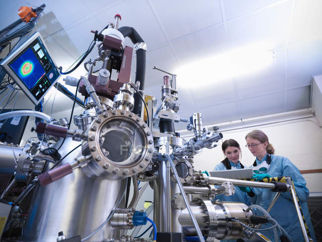 Cientistas trabalhando juntos na frente da câmara de ciência dos materiais — Fotografia de Stock