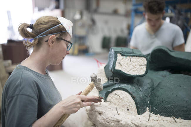 Gießereiarbeiterin entfernt Schimmel aus Bronzeskulptur in Bronzegießerei — Stockfoto