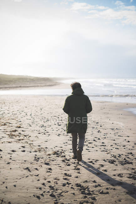 Vue arrière de l'homme se promenant sur la plage venteuse, Sorso, Sassari, Sardaigne, Italie — Photo de stock