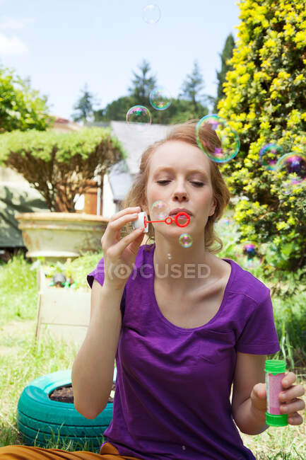 Femme soufflant des bulles dans le jardin — Photo de stock