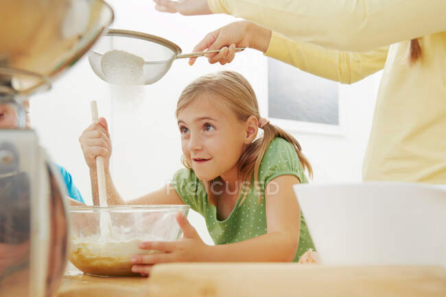 Cuisson des enfants, tamisage de la farine dans un bol de mélange — Photo de stock