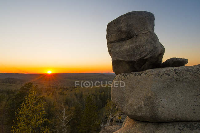 Felsbrocken auf Klippe mit Sonnenuntergang über Horizont — Stockfoto