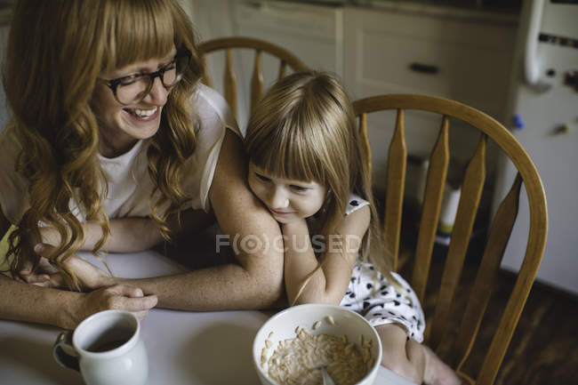 Mutter und Tochter kuscheln am Frühstückstisch — Stockfoto