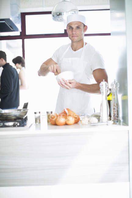Portrait of male chef mixing with mortar and pestle in commercial kitchen — Stock Photo