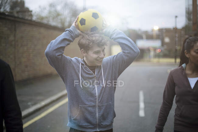 Gruppo di adulti che camminano per strada, tenendo il calcio — Foto stock