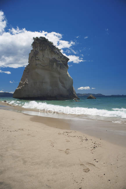 Скелясте утворення на піщаному пляжі з яскравим блакитним небом — стокове фото