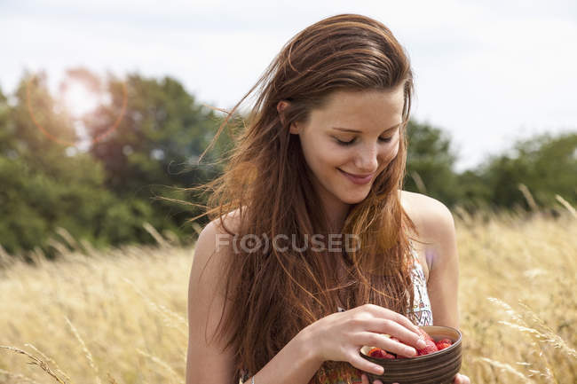 Junge Frau hält Schale mit frischem Obst im Feld — Stockfoto