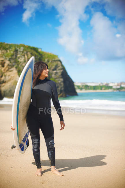 Surfista llevando tabla en la playa - foto de stock