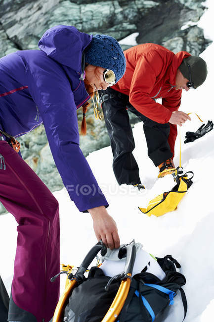 Montañeros preparando equipo en montaña cubierta de nieve - foto de stock
