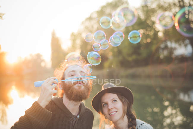 Jovem casal soprando bolhas — Fotografia de Stock