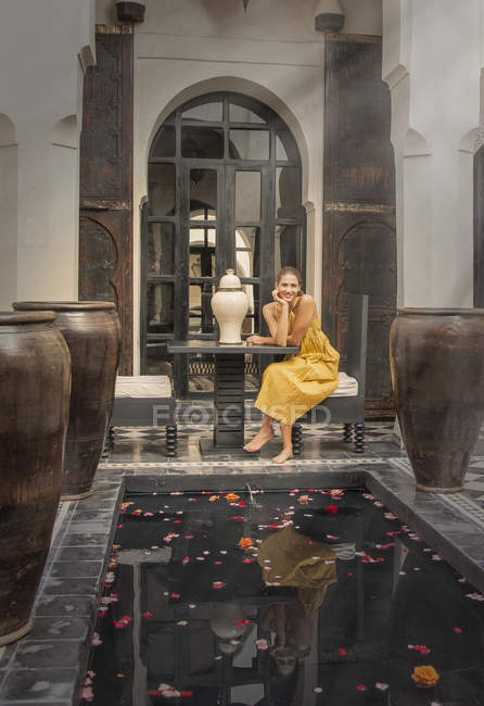 Young woman sitting by petal covered water feature, Marrakesh, Morocco — Stock Photo