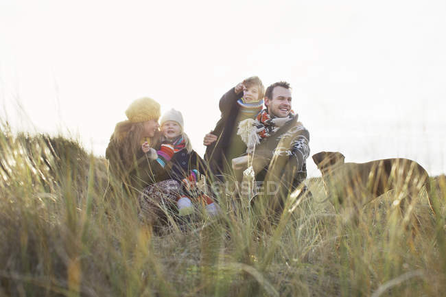 Couple adulte moyen dans les dunes de sable avec leur fils, leur fille et leur chien — Photo de stock