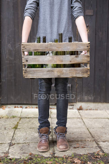 Adolescente carregando garrafas vazias em caixa de madeira — Fotografia de Stock